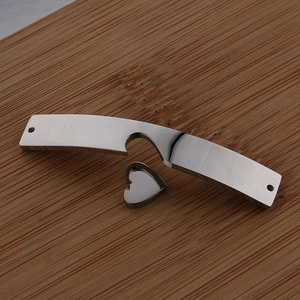 Macro detail of polished stainless steel heart charm and curved bar on wood surface