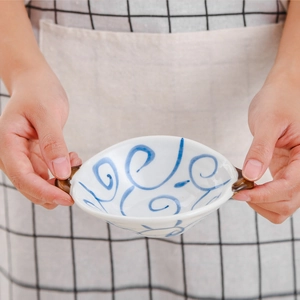 Ceramic double-handled bowl with blue swirl pattern held by hands for home serving