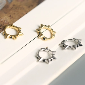 Detail of 925 sterling silver hoop earrings with punk spikes and black crystals in gold and silver