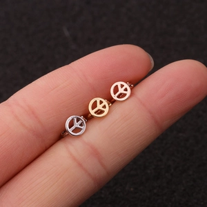 Gros plan de trois créoles avec symbole de paix en argent, or et or rose tenues par les doigts