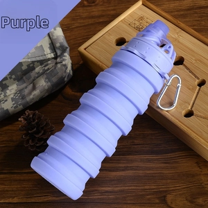 Purple collapsible silicone water bottle with silver carabiner on rustic wooden tray