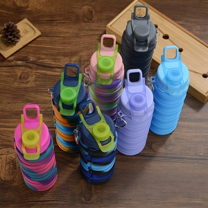 Flat lay of colorful collapsible silicone water bottles with metal carabiners on wood