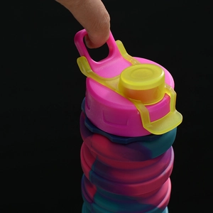 Detail of pink and blue collapsible silicone water bottle with yellow carrying handle