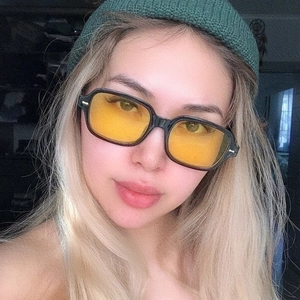 Close-up of retro square sunglasses with thick black frames and yellow lenses on model