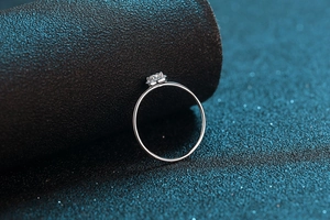 Macro shot of 925 silver moissanite ring with round cut stone on a blue glitter surface