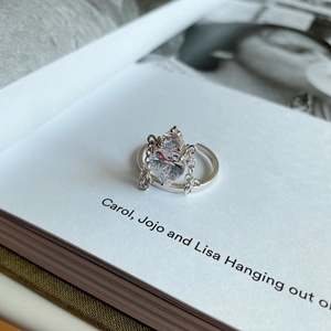 Close-up of elegant crown ring with pear-shaped zircon on white book pages
