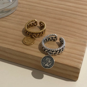 Detailed shot of chain texture rings with Elizabeth II coin pendants in gold and silver