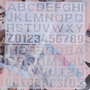 Flat lay of alphanumeric silicone molds for resin casting on a vintage paper background