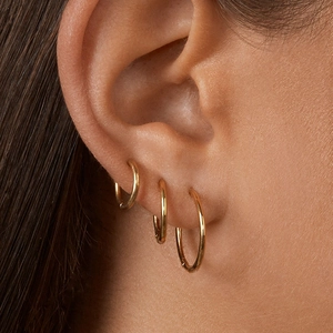 Close-up of three 18K gold stainless steel hoop earrings worn on a model's ear