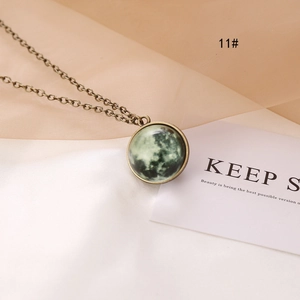 Detail of vintage bronze necklace featuring green glowing universe moon pendant texture