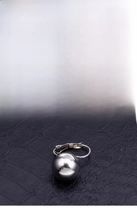 Detailed view of polished stainless steel sphere clip-on earrings on black texture