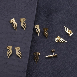 Golden angel wing stud earrings in a minimalist totem design on black leather backdrop