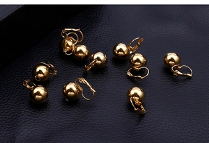 Detail view of scattered gold spherical leverback earrings on dark leather background