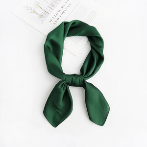 Detail view of dark green silk scarf tied in a decorative knot on a white background