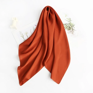 Flat lay of an orange silk satin square scarf with smooth texture and soft luster