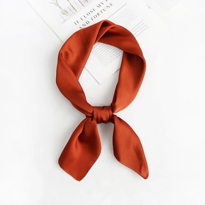 Detail of rust orange satin square scarf featuring silky texture and elegant knot