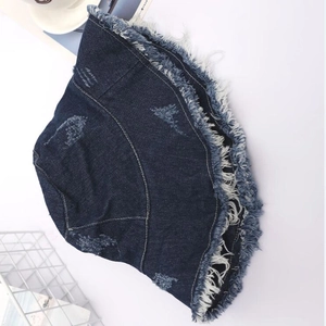 Close-up of dark blue denim bucket hat with distressed holes and fringe frayed edges