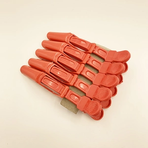 Set of six red professional hair sectioning alligator clips on display cardboard