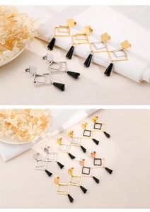 Detailed view of titanium steel geometric drop earrings with black conical pendants