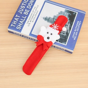 Nahaufnahme eines Weihnachts-Klapparmbands mit Plüschbär auf hellem Holzhintergrund