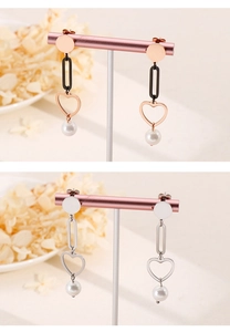 Detail view of heart and pearl drop earrings in rose gold and silver stainless steel