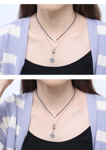 Détail du collier double rang avec pendentif coeur, perle blanche et cordon en cuir noir