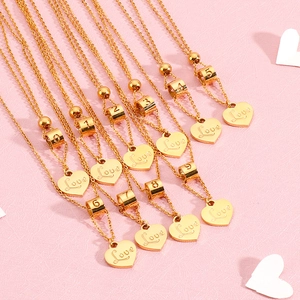 Golden heart necklace with Love charm and number pendants on a soft pink background