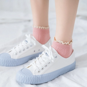 Pink Japanese style cotton crew socks with white lace trim worn with white canvas shoes