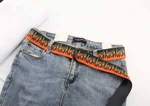 Close-up of hip-hop canvas belt featuring orange flame print and black double ring buckle