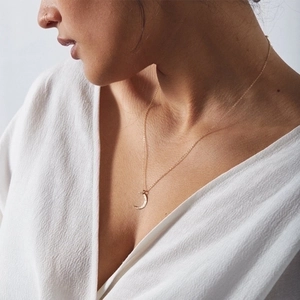 Close-up of a minimalist gold moon pendant necklace on a model for a stylish look
