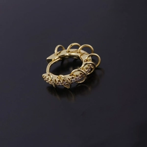 Pendiente de aro dorado con remaches y circonitas con dijes de anillo en fondo oscuro