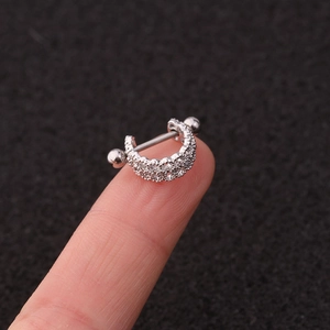 Macro shot of silver U-shaped earring with flower zircon stud on finger