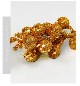 Macro view of gold Christmas berry picks with shimmering glitter and sequins detail