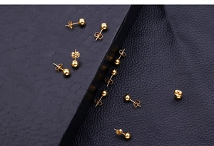 Polished 18k gold plated stainless steel ball stud earrings on a dark texture