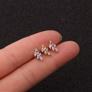 Macro shot of three leaf-shaped cartilage earrings in silver, gold, and rose gold finishes
