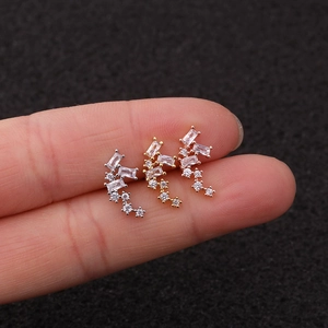 Close-up of three zirconia cartilage stud earrings in silver, gold, and rose gold finishes