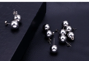 Detailed view of silver stainless steel ball stud earrings on a black textured surface