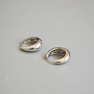 Orecchini a cerchio spessi in argento lucido con design metallico curvo minimalista