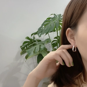 Detail of 925 sterling silver geometric U-shaped earrings on a model with green accents