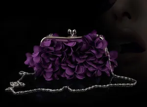 Close-up of deep purple evening clutch with 3D floral petals and silver chain strap