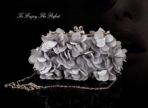 Detail of grey floral evening clutch bag with fabric petals and metal chain strap