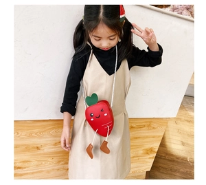 Detailed close-up of a red carrot-shaped mini crossbody bag with cute face and dangling legs