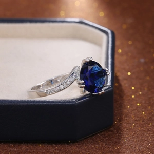Makroaufnahme: Ring mit ovalem blauem Edelstein und seitlichem Diamantbesatz