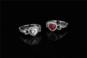 Detail of heart-shaped rings with red and white zircons on infinity band