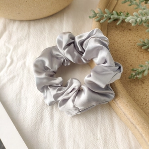 Detailed view of large silver grey satin scrunchie with shiny silk texture and elegant folds