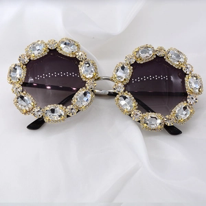 Detail of oversized gold sunglasses with crystal rhinestones on white silk fabric