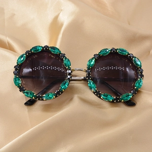 Detailed view of round oversized sunglasses with green horse-eye crystals and rhinestones