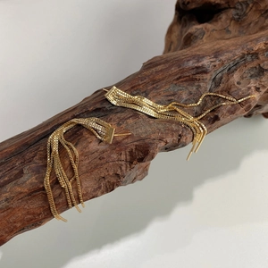 Macro shot of 925 silver golden tassel earrings hanging on rustic wood decoration