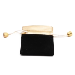 Detail of a black velvet jewelry pouch with golden satin top and metal drawstring ends