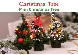Three 20cm mini Christmas trees with red flowers, bells and snow on green cloth bases